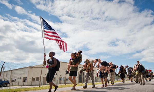 Participants march past the vehicle maintenance facility carrying simulated wounded personnel 