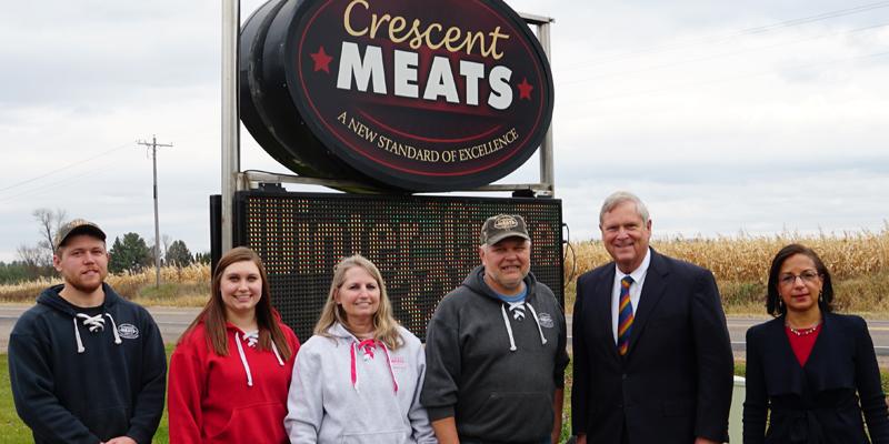 U.S. Secretary of Agriculture and other s standing in front of the Crescent Meats sign