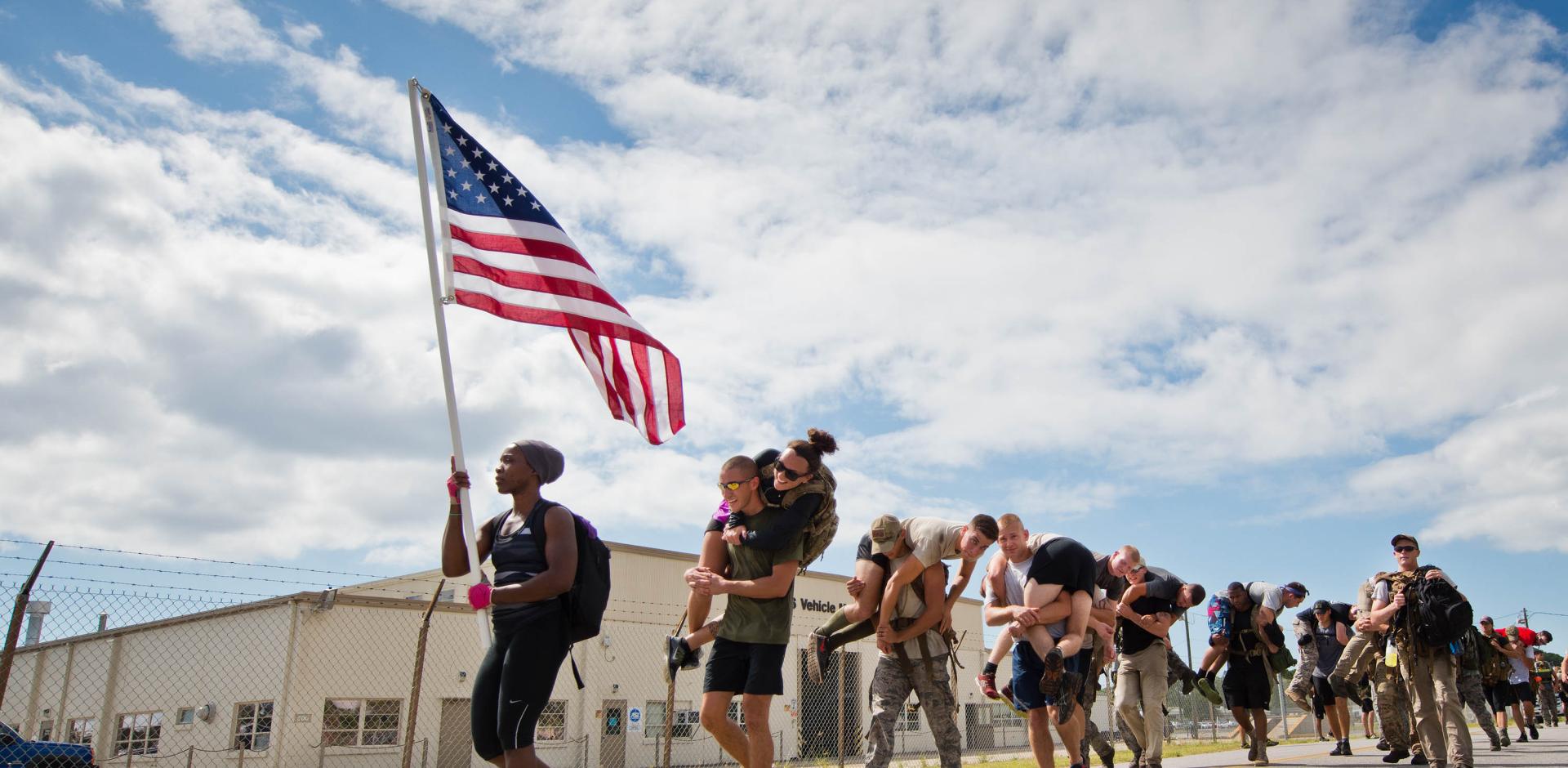 Participants march past the vehicle maintenance facility carrying simulated wounded personnel 